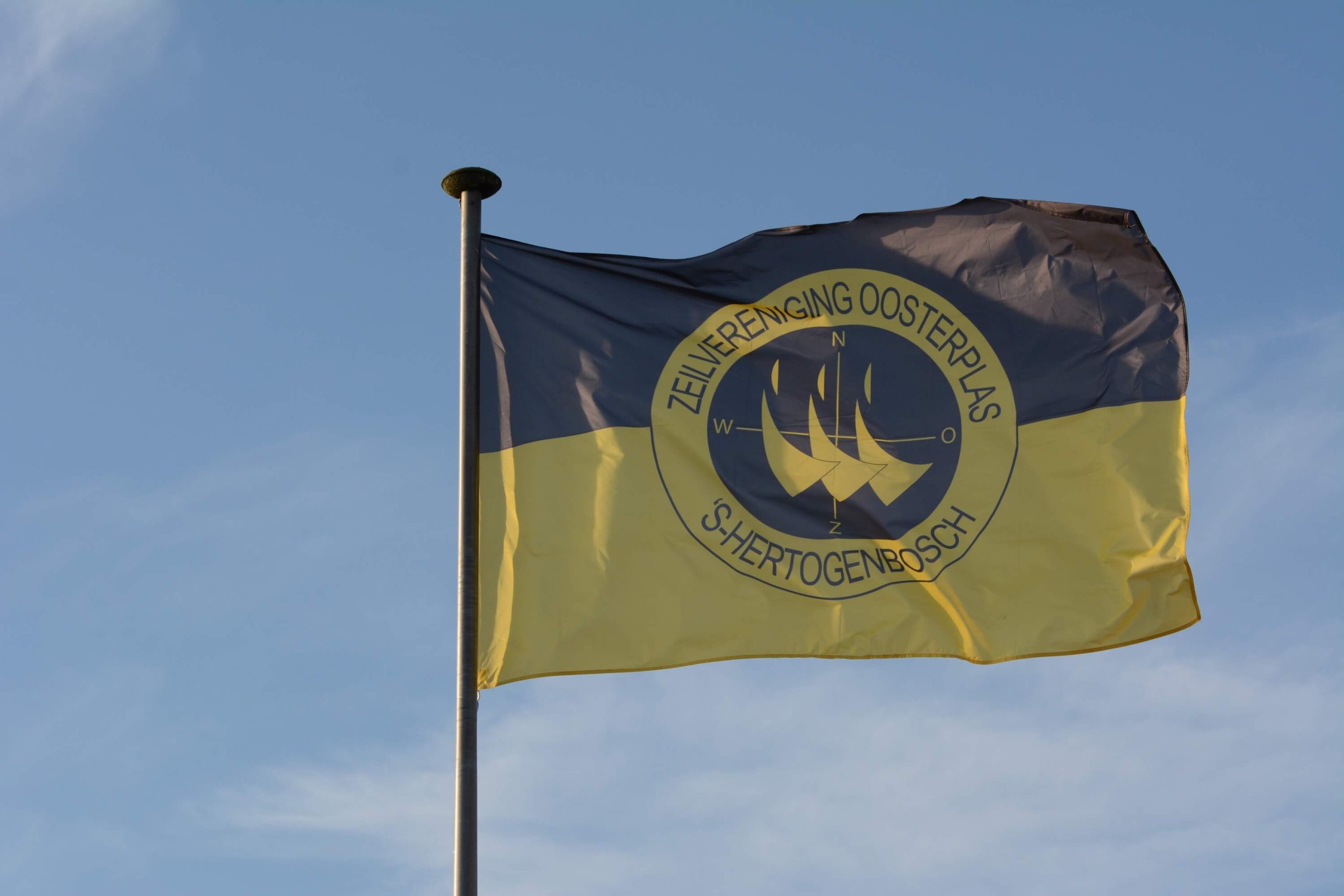 De blauw gele ZVO vlag wappert tegen een blauwe lucht.