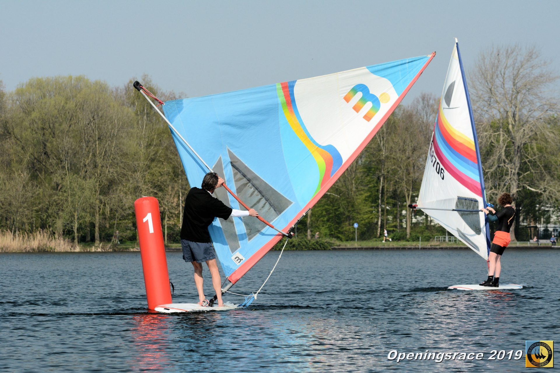 Windsurfers varen bij een rode wedstrijdboei tijdens de Openingsrace ZVO 2019.