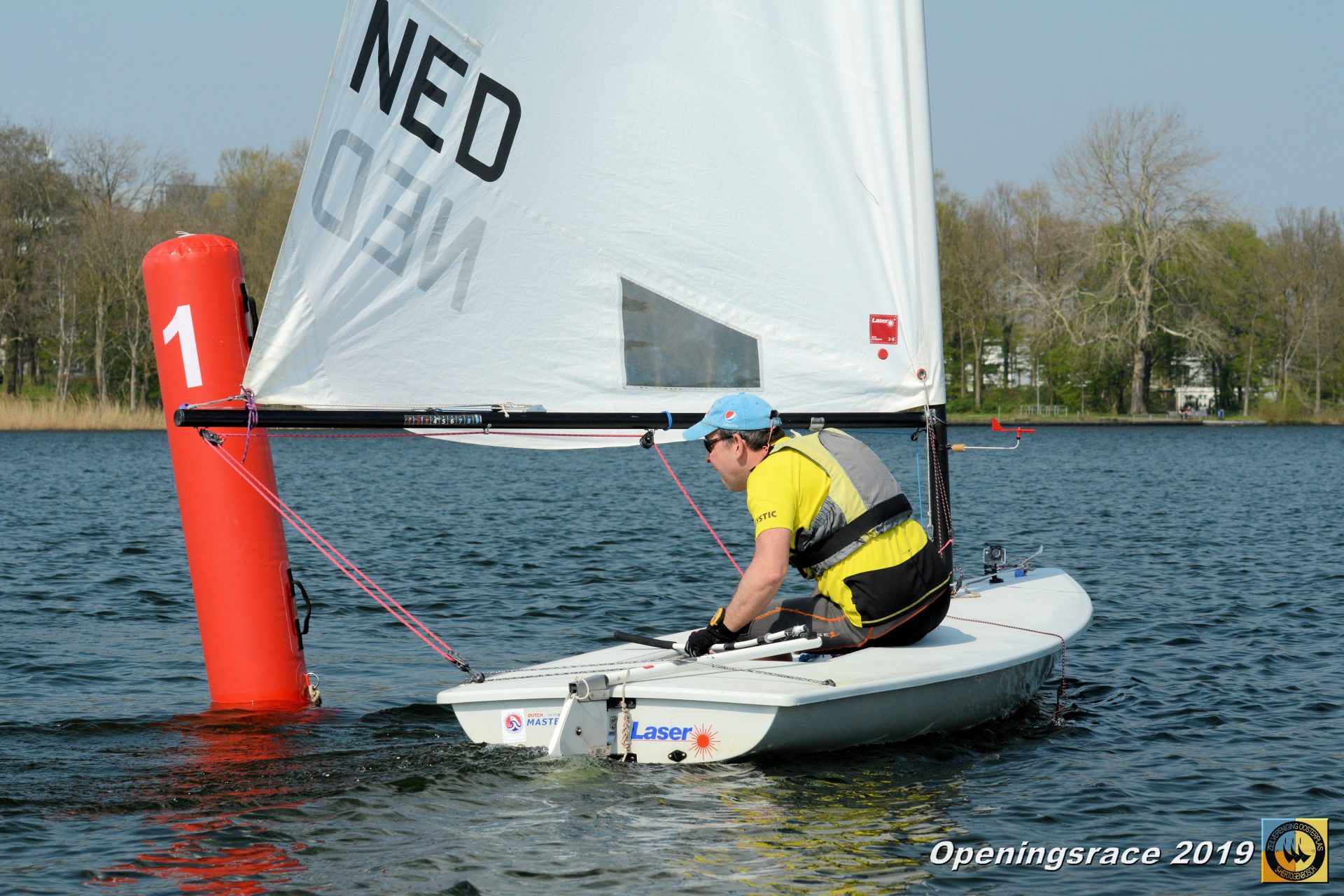 Een zeiler in een geel zwemvest vaart langs een rode boei tijdens de Openingsrace ZVO 2019.