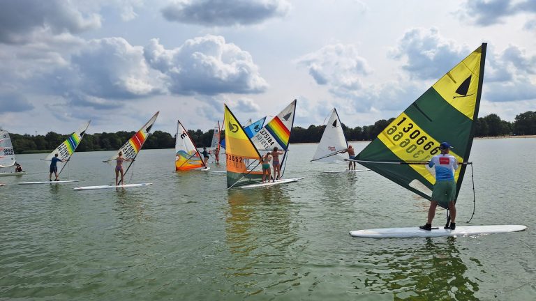 Groep windsurfers met kleurrijke zeilen vaart op de Oosterplas.