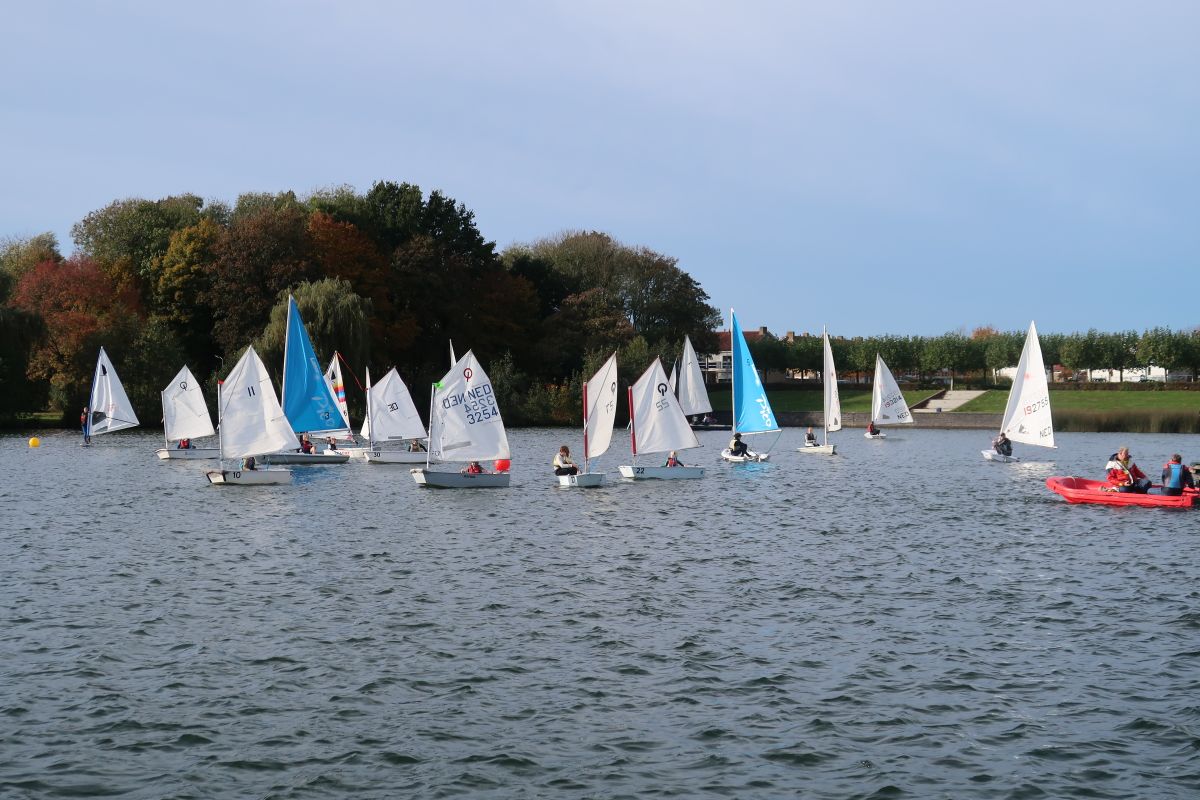 Veel Optimisten varen op de Oosterplas met een rode reddingsboot naast het veld.