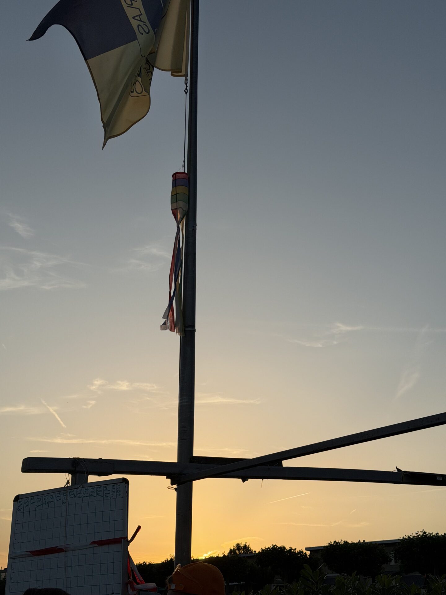 Een vlag en mast staan als silhouet tegen de zonsondergang tijdens Midzomernacht 2026.