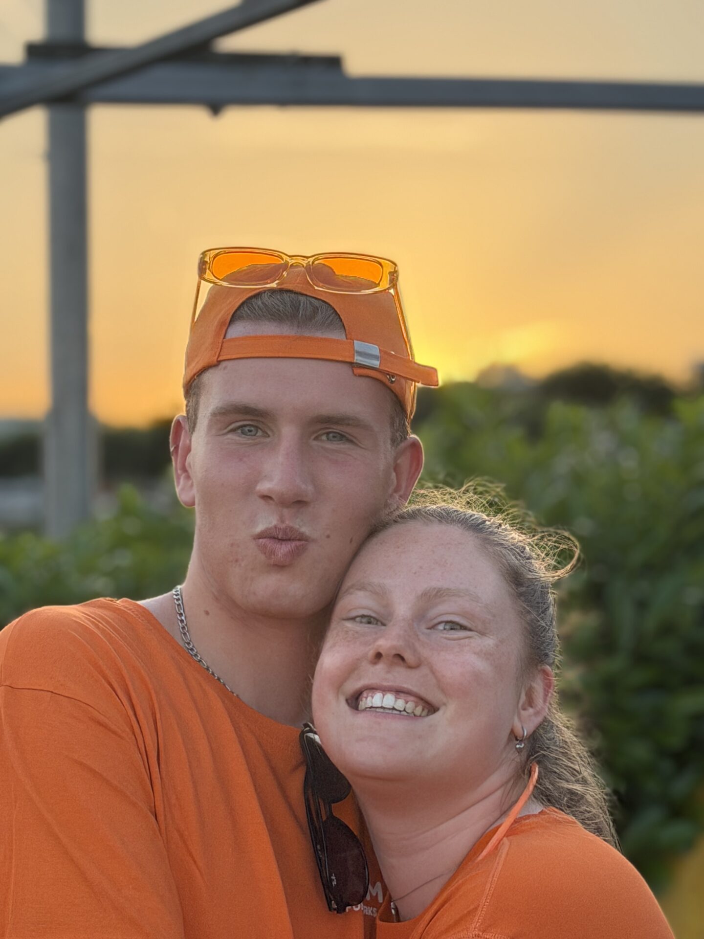 Twee deelnemers in oranje kleding poseren bij avondlicht tijdens Midzomernacht 2026.