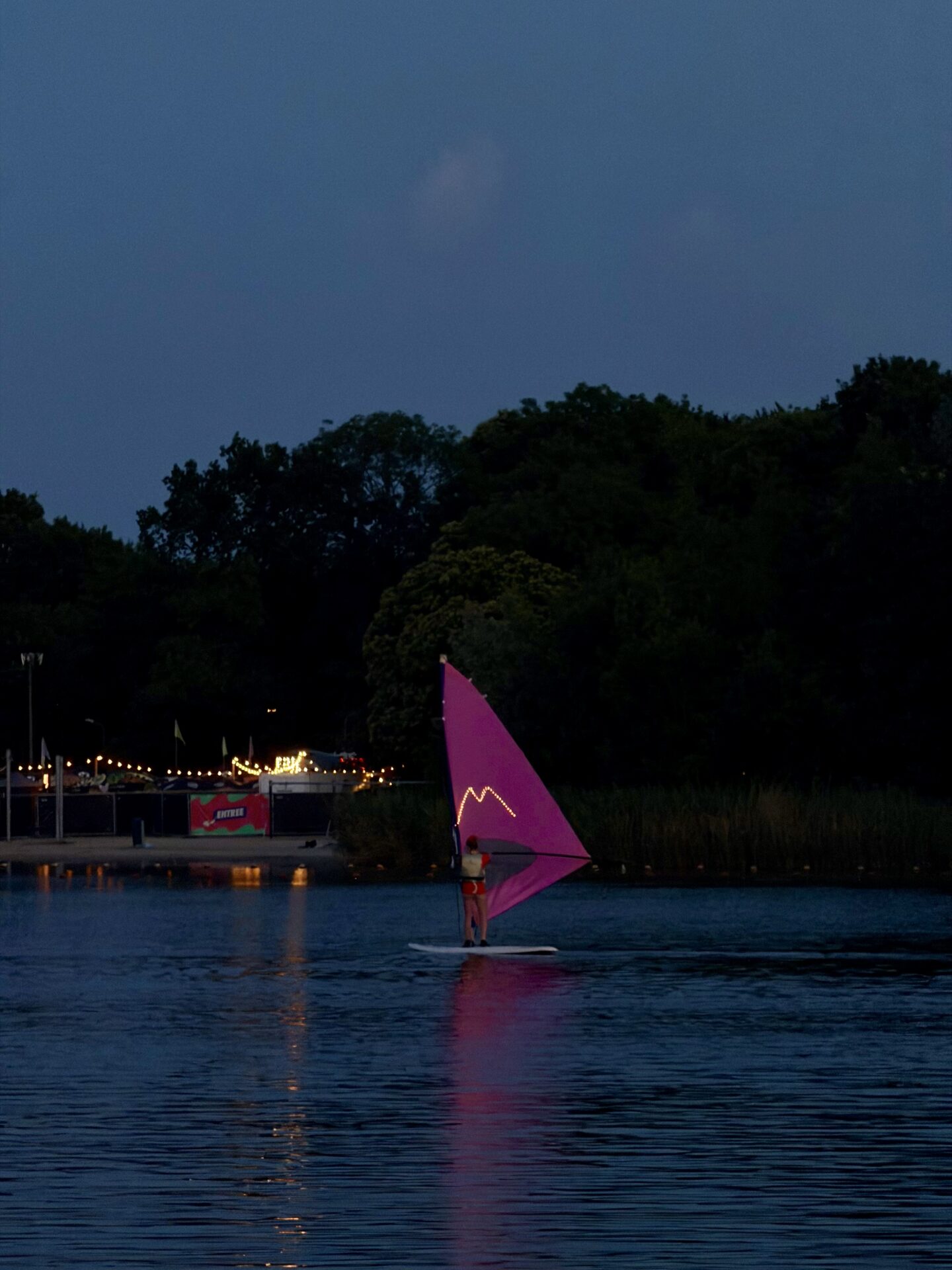 Een roze windsurfzeil vaart bij avondlicht op de Oosterplas tijdens Midzomernacht 2026.
