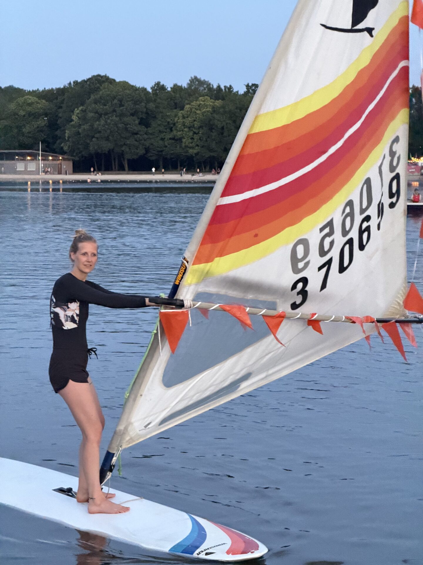 Een windsurfer staat op een surfplank met een kleurrijk zeil tijdens Midzomernacht 2026.