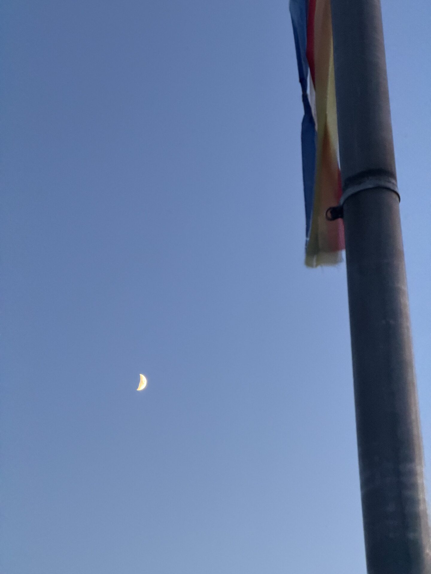 Een maan staat naast een vlaggenmast in de avondlucht tijdens Midzomernacht 2026.