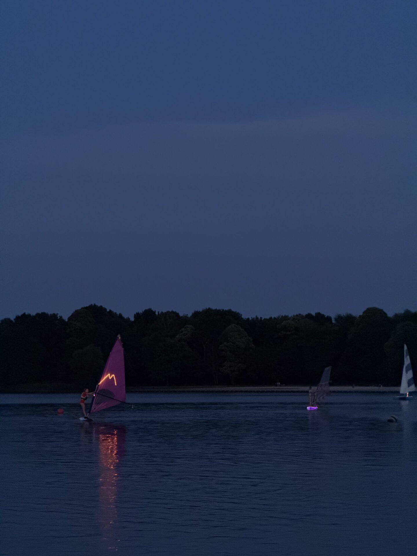 Een roze windsurfzeil is zichtbaar op donker water tijdens Midzomernacht 2026.